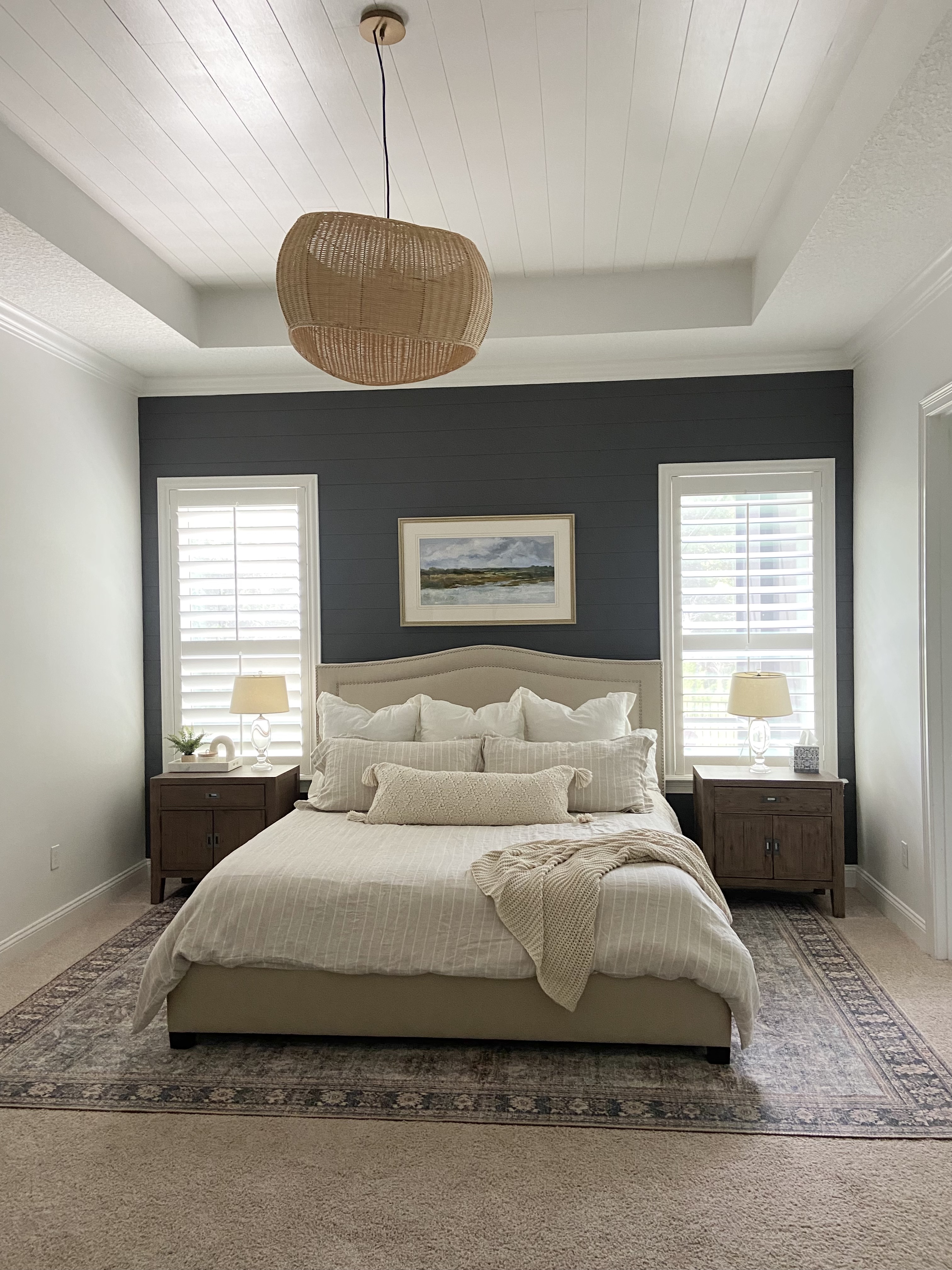 This dark blue accent wall features two windows on either side of the bed, creating the perfect balance of symmetry.