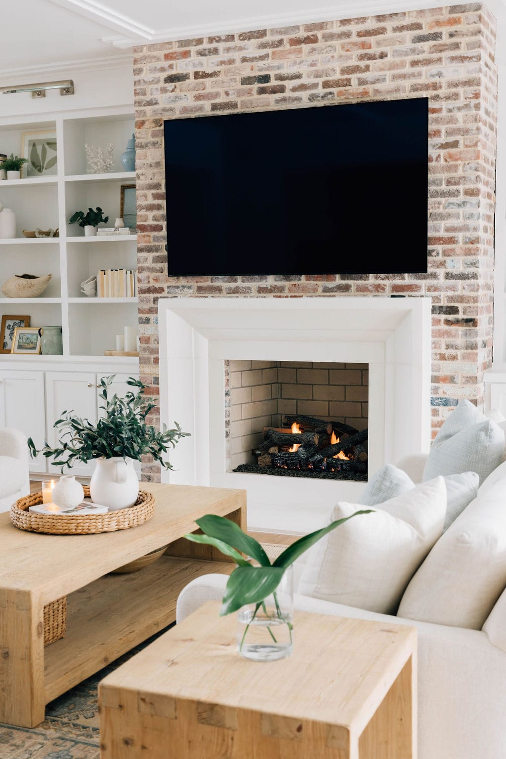  A cozy living room featuring elegant white furniture and a warm fireplace, creating a welcoming atmosphere. Designed by Welcome Home Styling, an interior design company in Jacksonville.