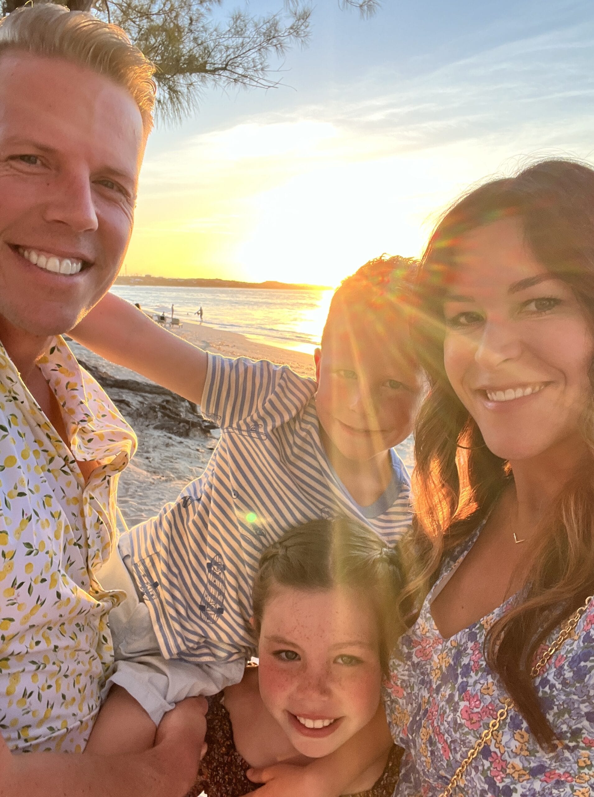 Smiling happy Woodward family standing on the beach in Greece. 