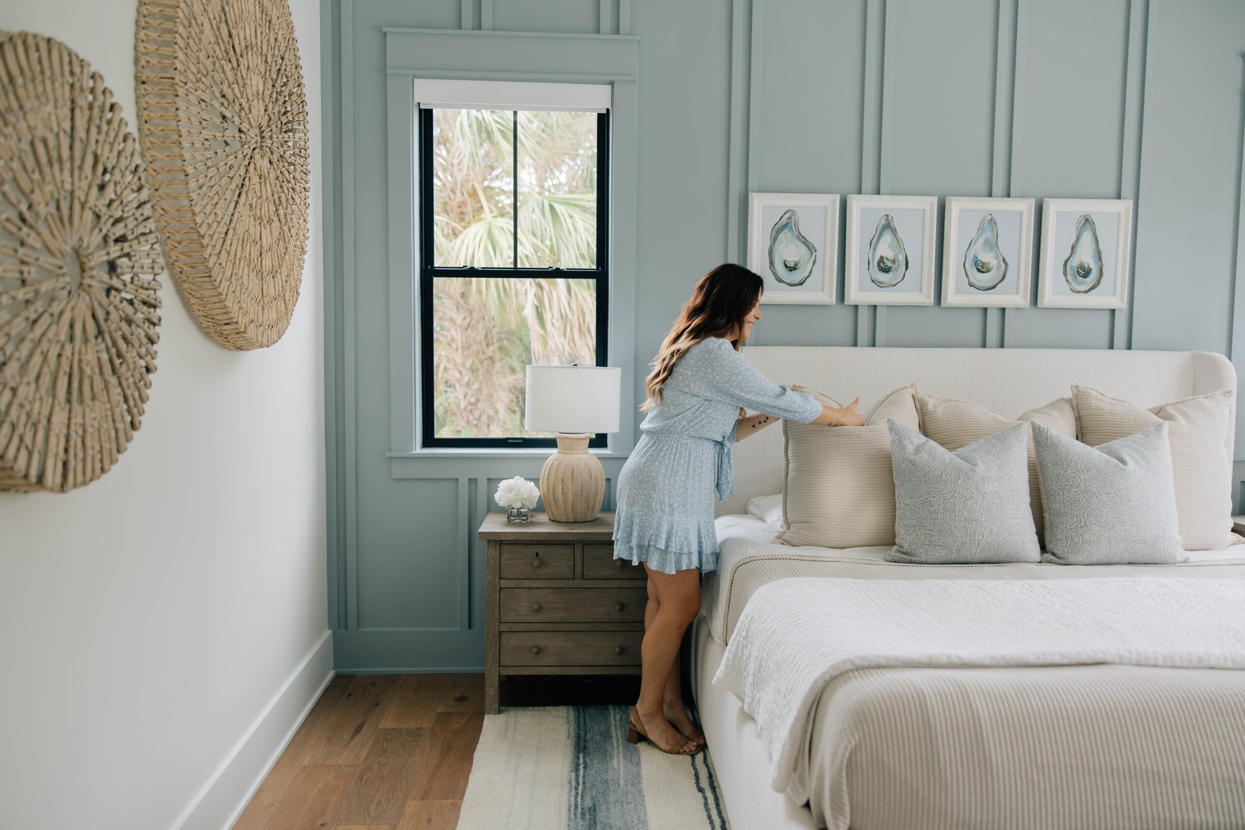 Interior designer Jessica Woodward styles a neatly made bed, showcasing a serene bedroom environment.