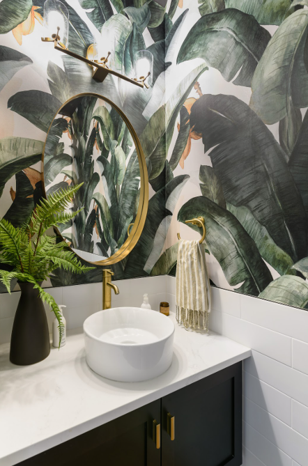 This bold tropical wallpaper gives a big dose of style to this small space. Gold accents and a clean white marble countertop and bowl sink work to tie the space together.