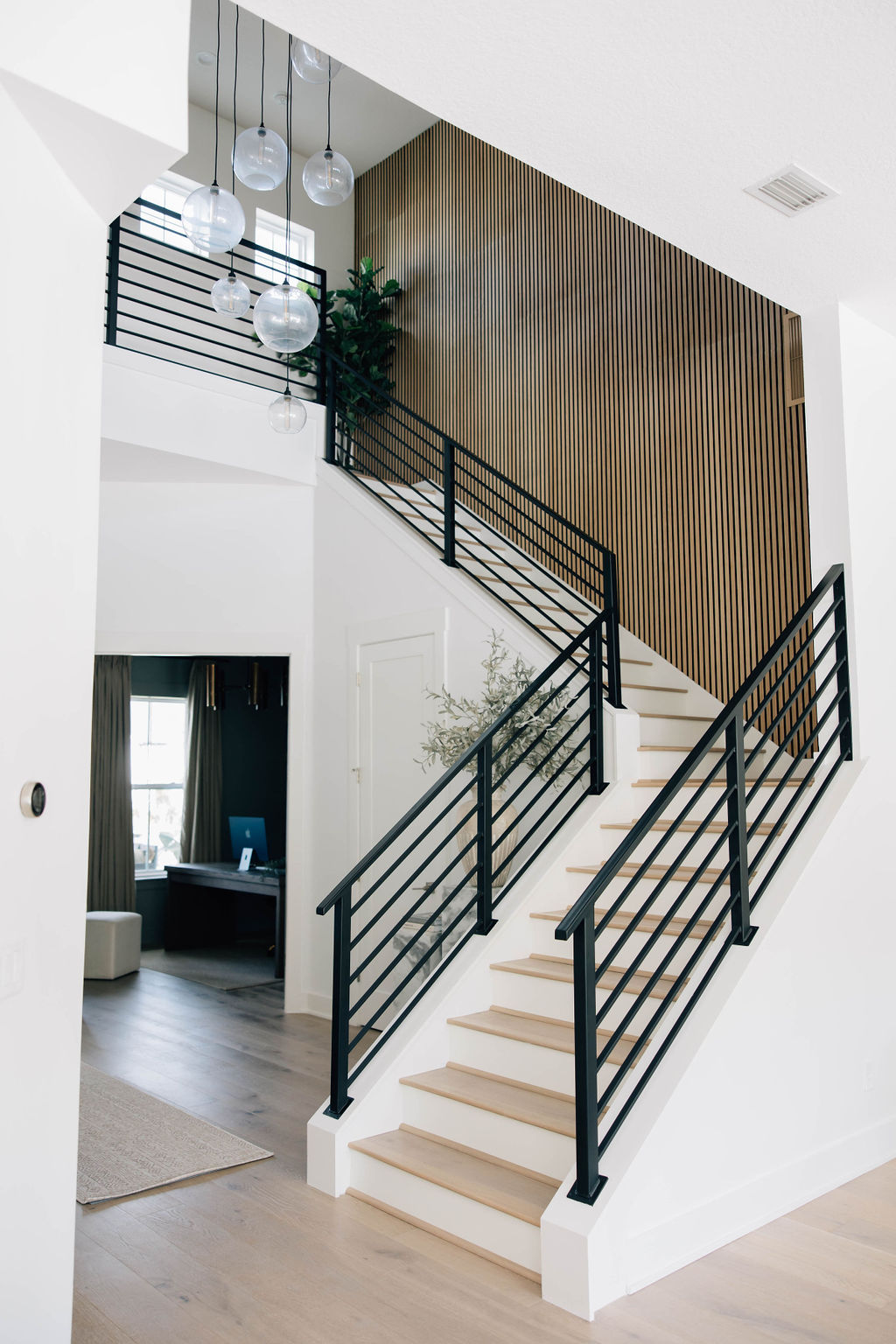 staircase in entryway with metal railings and paneled wall treatment.