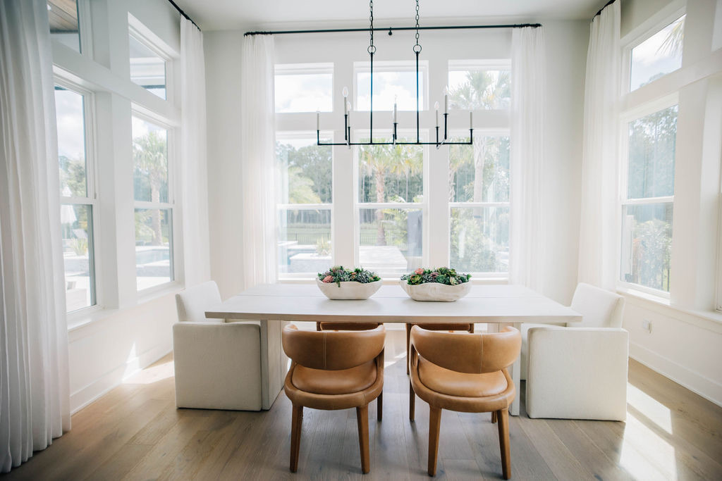 Coastal casual dining room with ample natural light, simplistic lighting fixtures, airy drapes, and custom dining set. 