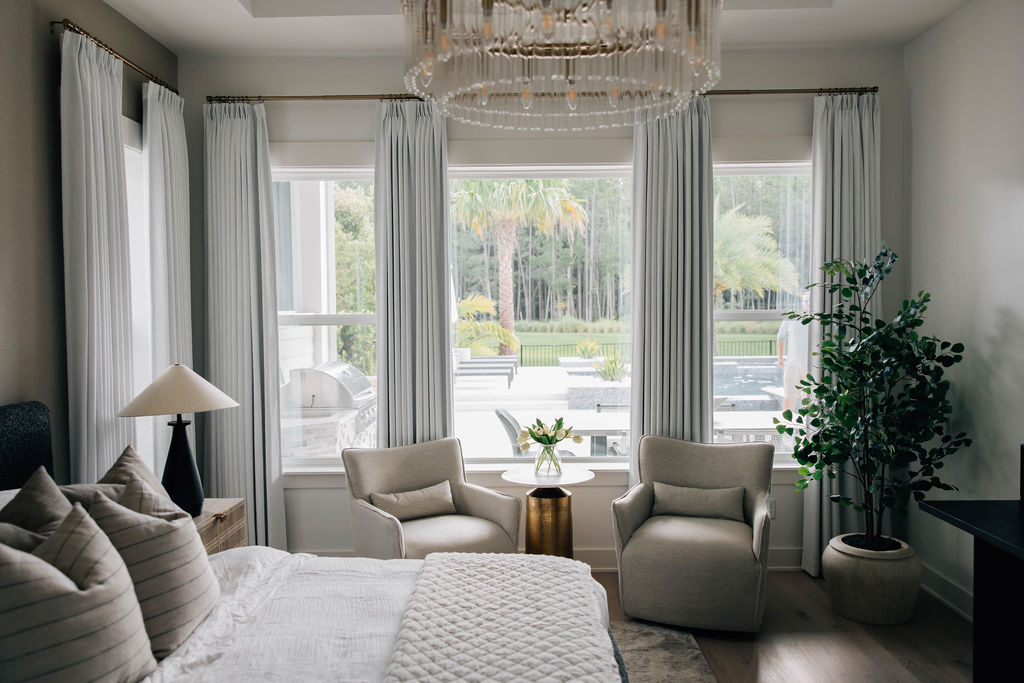 sophisticated and airy primary suite with elegant chandelier, plush furnishings, and neutral color palette.