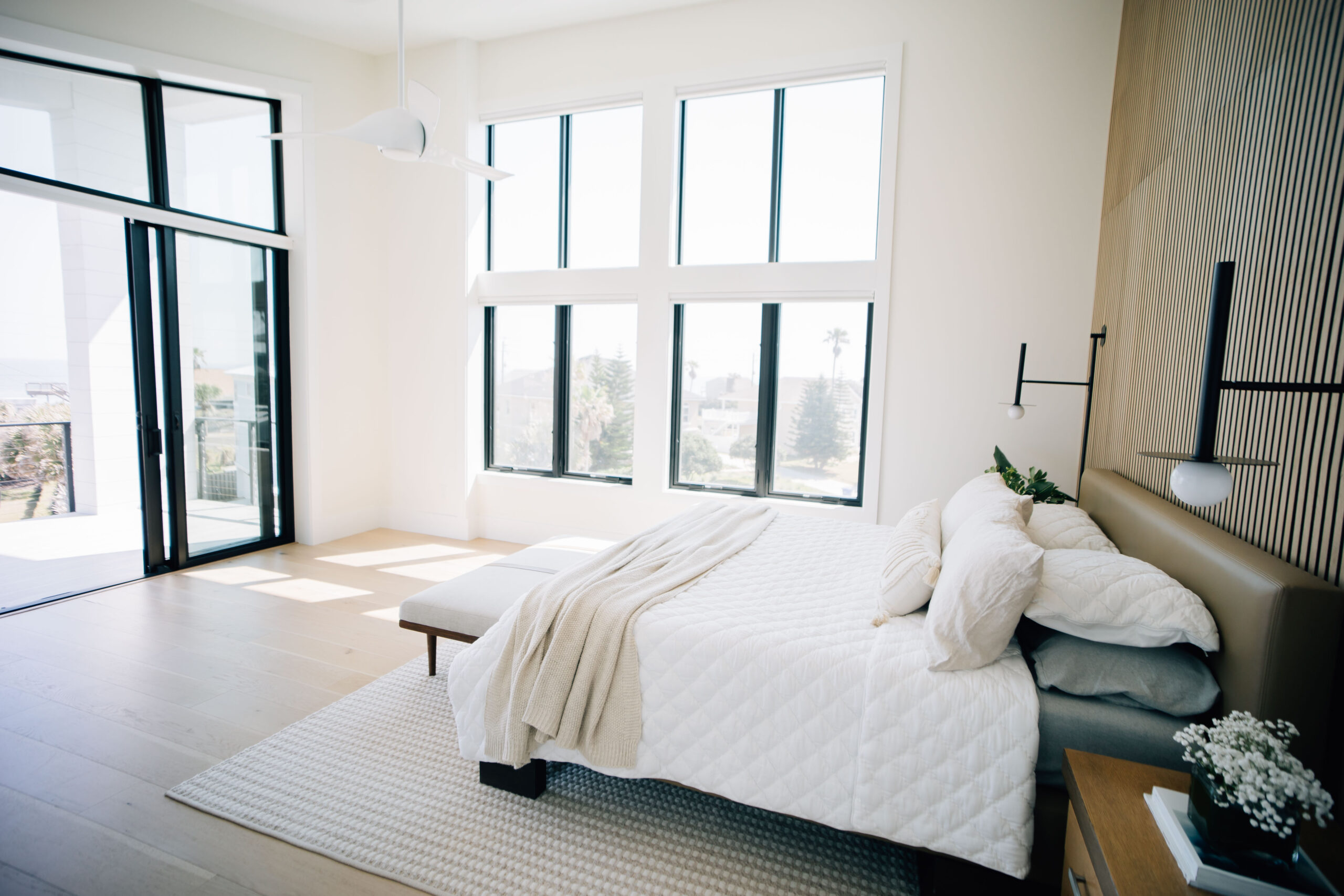 primary bedroom with ample natural light, a textured feature wall, and beautiful wood floors.