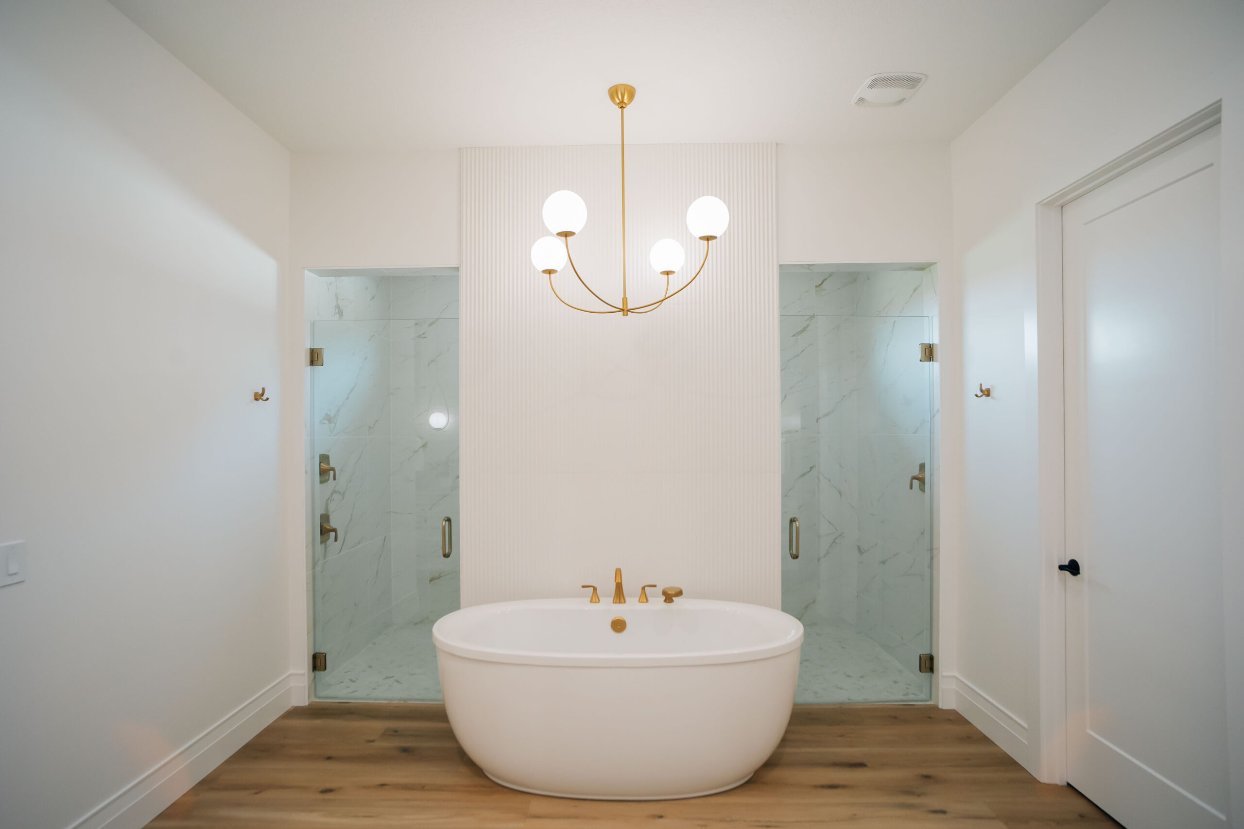 Spa-Like Primary Bathroom New interior design bathroom with double-entry shower, a free-standing tub, a modern light fixture, and natural wood floors create a luxurious space.