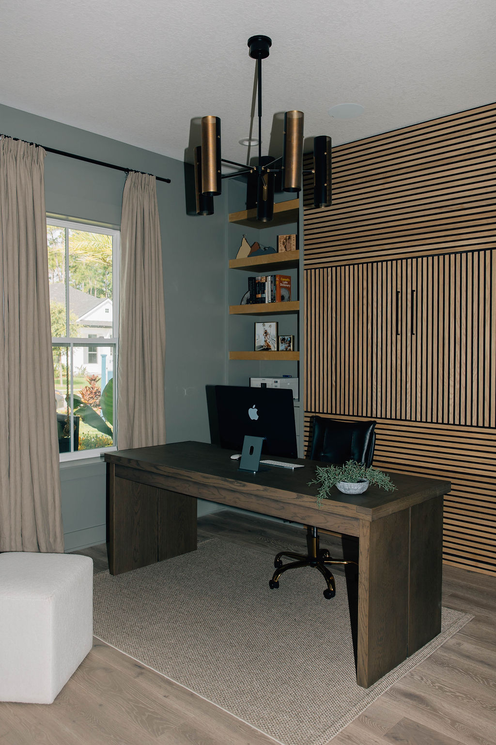 Contemporary home office redesign with a minimalist dark wood desk, custom shelving, and a paneled accent wall that turns into a Murphy bed.