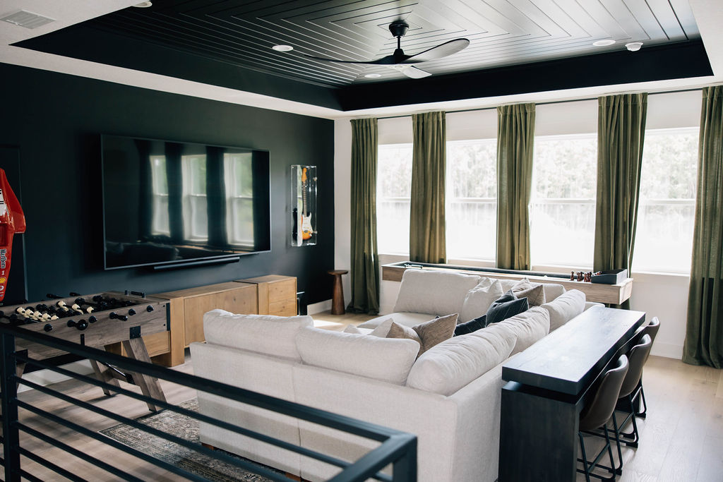 Spacious family room featuring a large sectional, game tables, and media setup, expertly styled for kids and adults by an interior decorator specializing in family-friendly interiors.