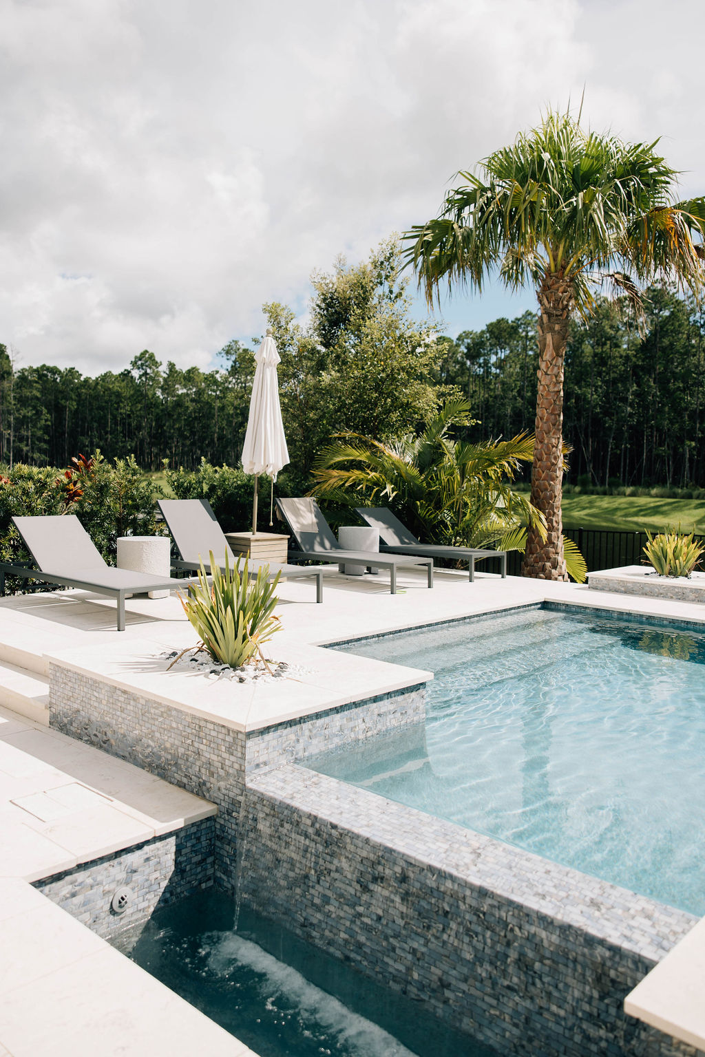 Beautiful Florida backyard with modern pool, tropical landscaping, and sun loungers, showcasing outdoor living by a St. Johns County interior design firm