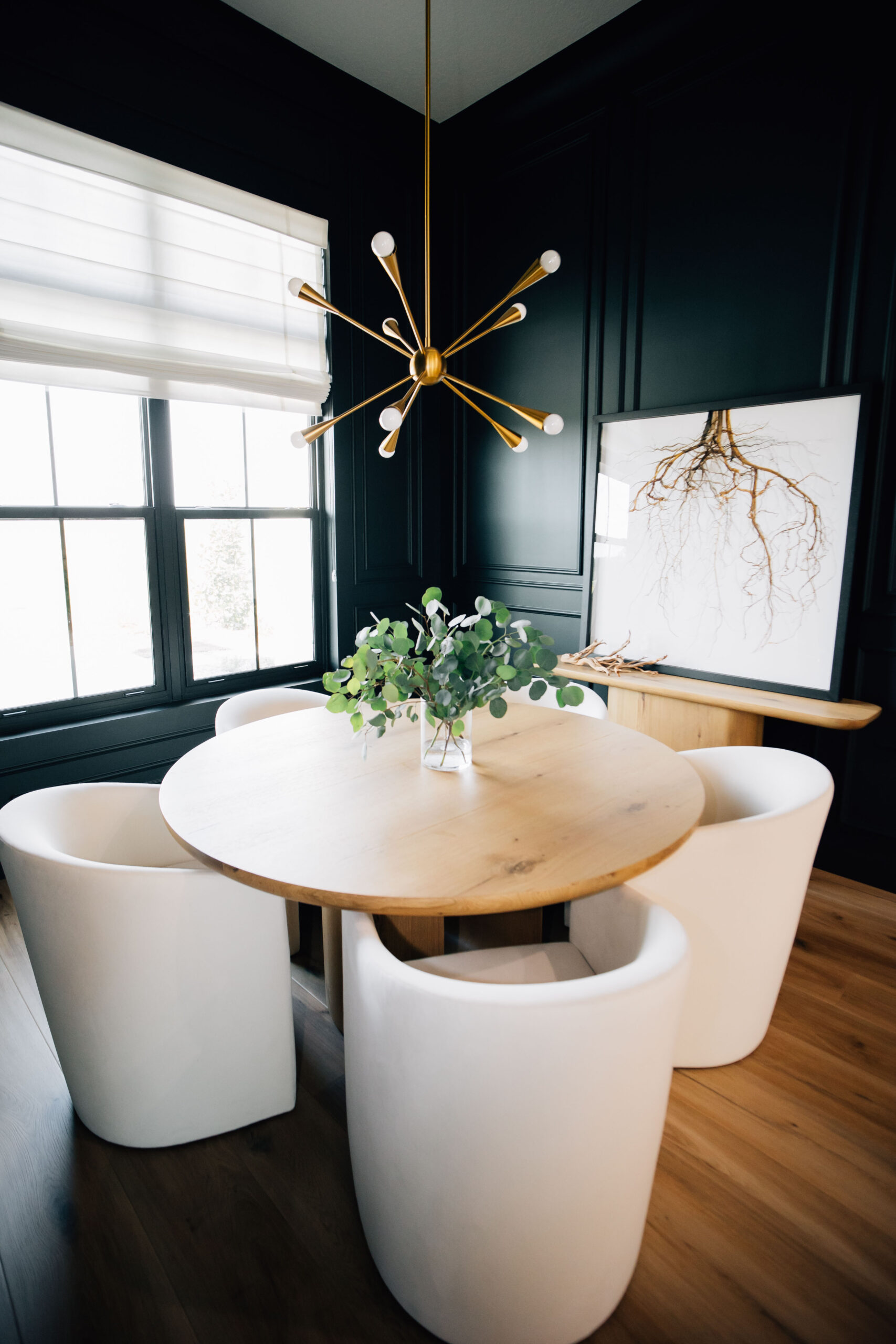Modern yet timeless kitchen with a wooden table, white chairs, and a modern light fixture.
