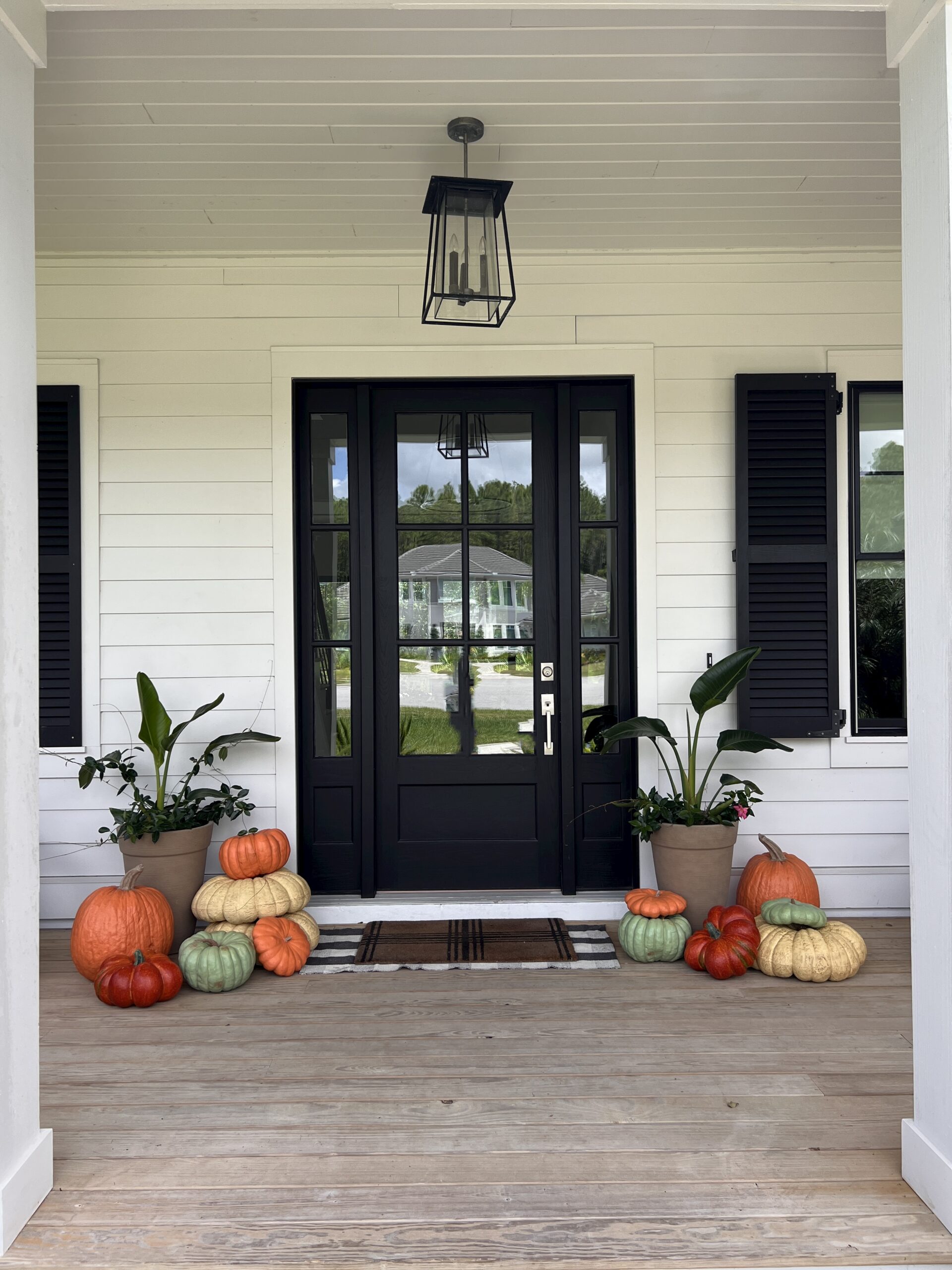 Front porch with stacked pumpkins and greenery arranged for not so scary Halloween entertaining and seasonal home decor.