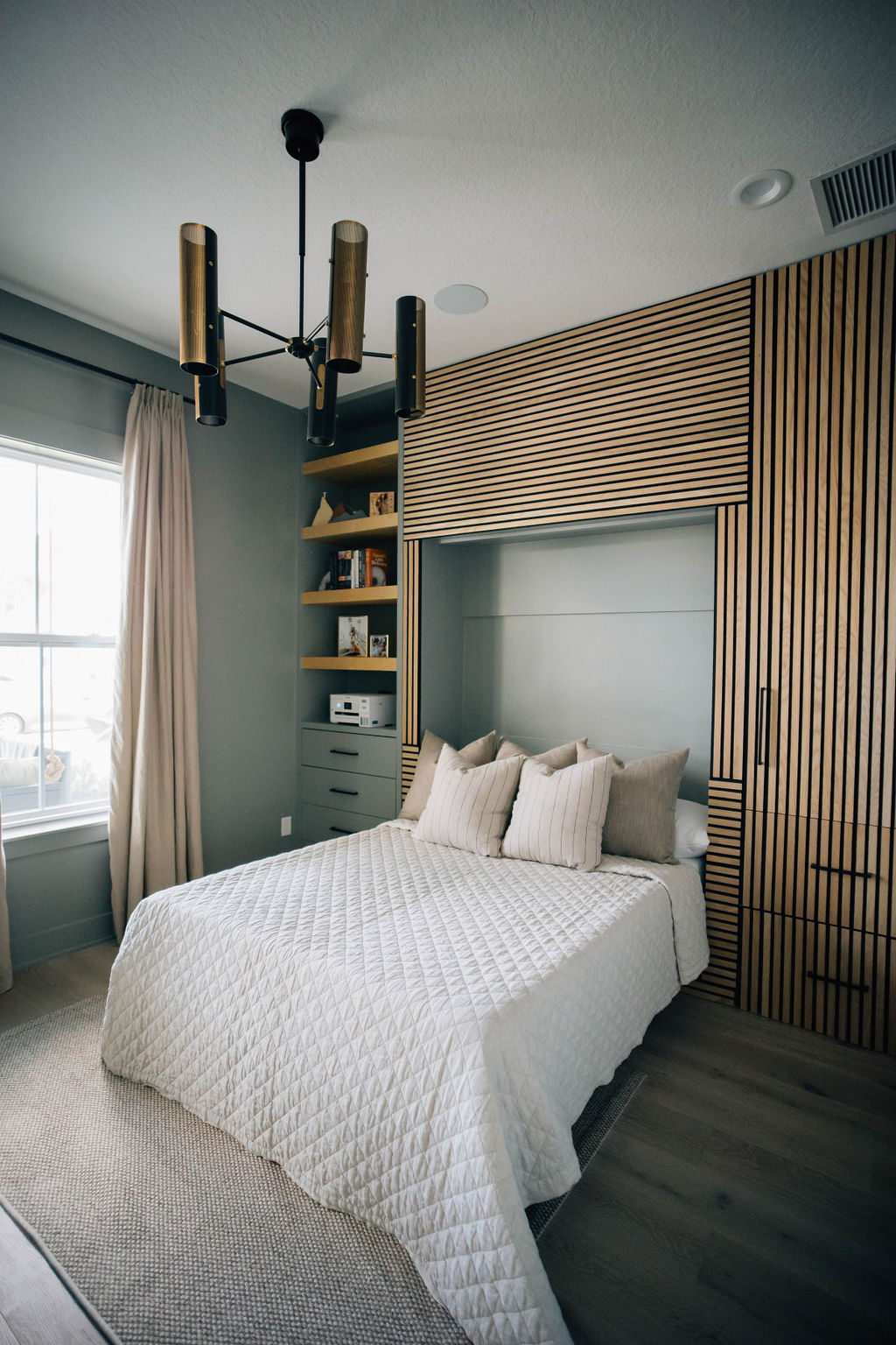 Guest bedroom with wood panel Murphy bed and built-in shelving.