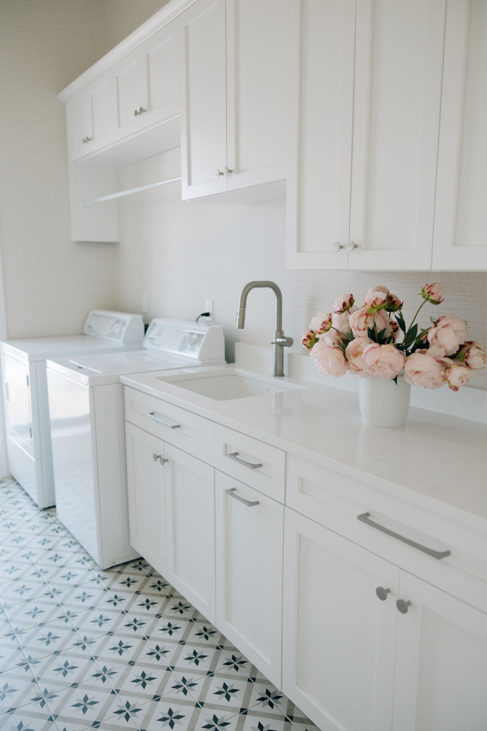 White laundry room with patterned tile and built-in cabinetry in a Jacksonville, FL home.