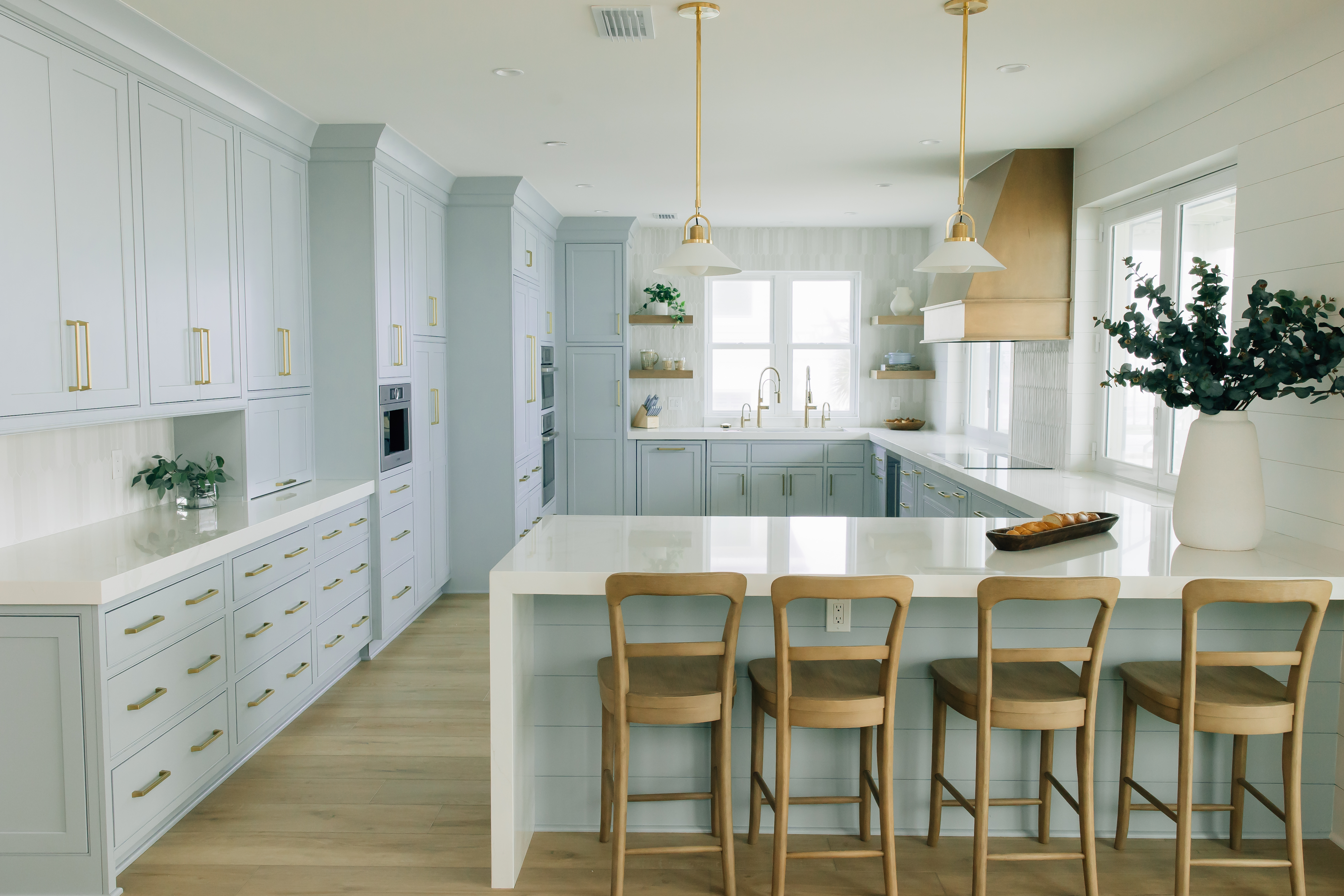 Bright coastal-inspired kitchen with light blue cabinetry, gold hardware, and a large white island designed by Jacksonville interior designer.