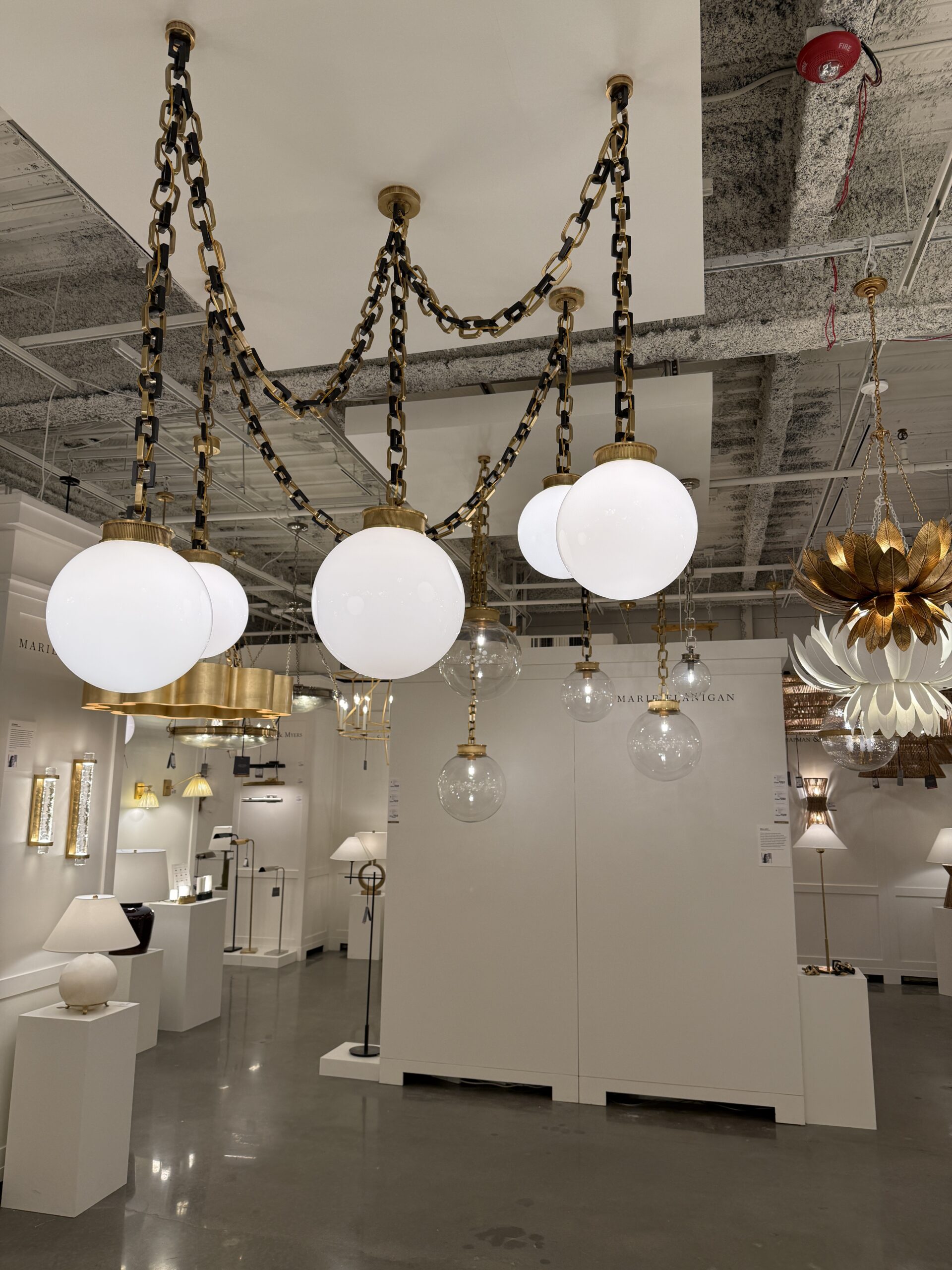 Modern swag lighting fixture with oversized globe bulbs, brass hardware, and decorative chains.