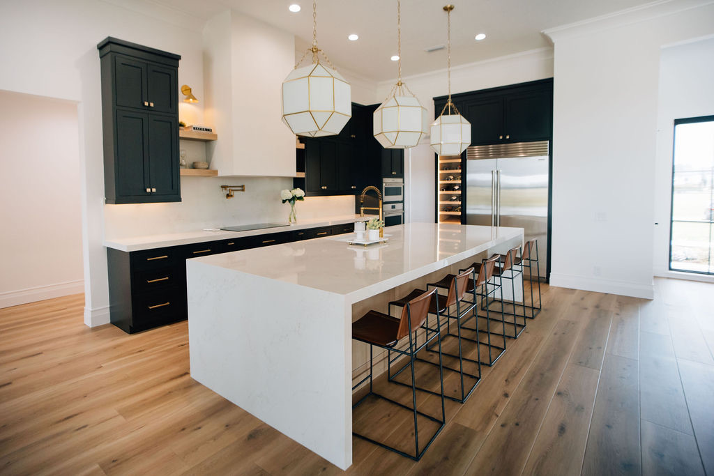 Beautifully designed kitchen with unique pendant lights, recessed lighting, and task lighting to make sure the counters and space are well-lit.
