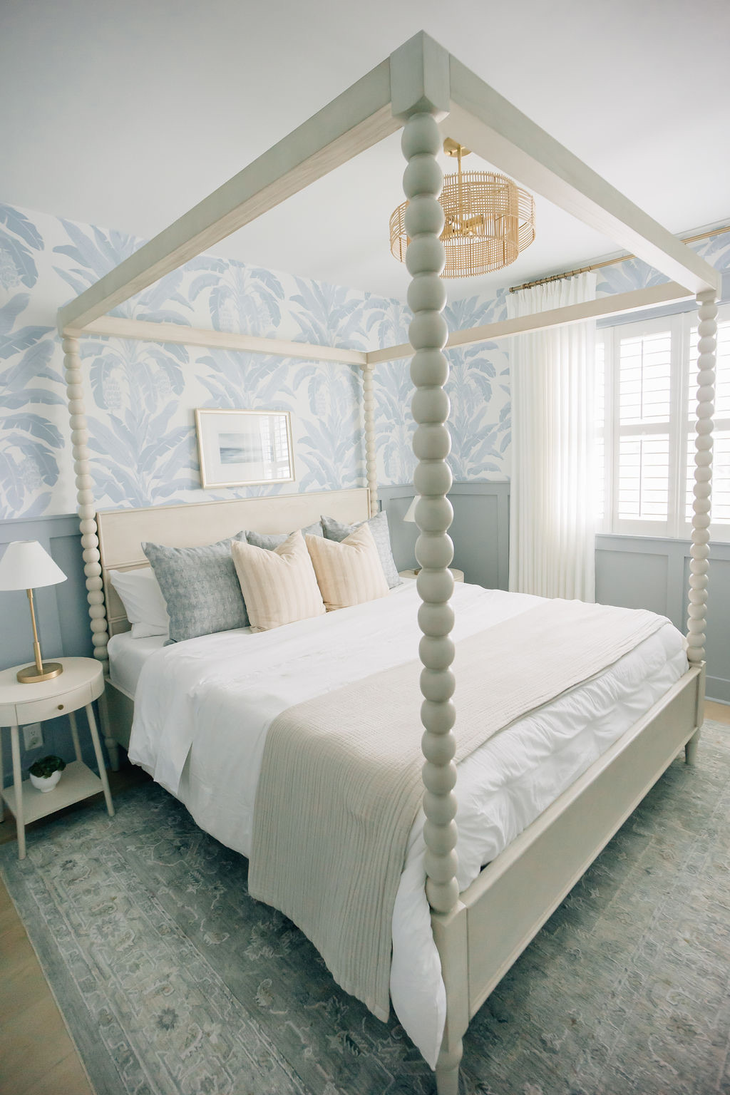 Coastal bedroom with soft blue wallpaper, layered white linens, and muted blue and white pillows, reflecting modern interior design trends in Ponte Vedra Beach homes.