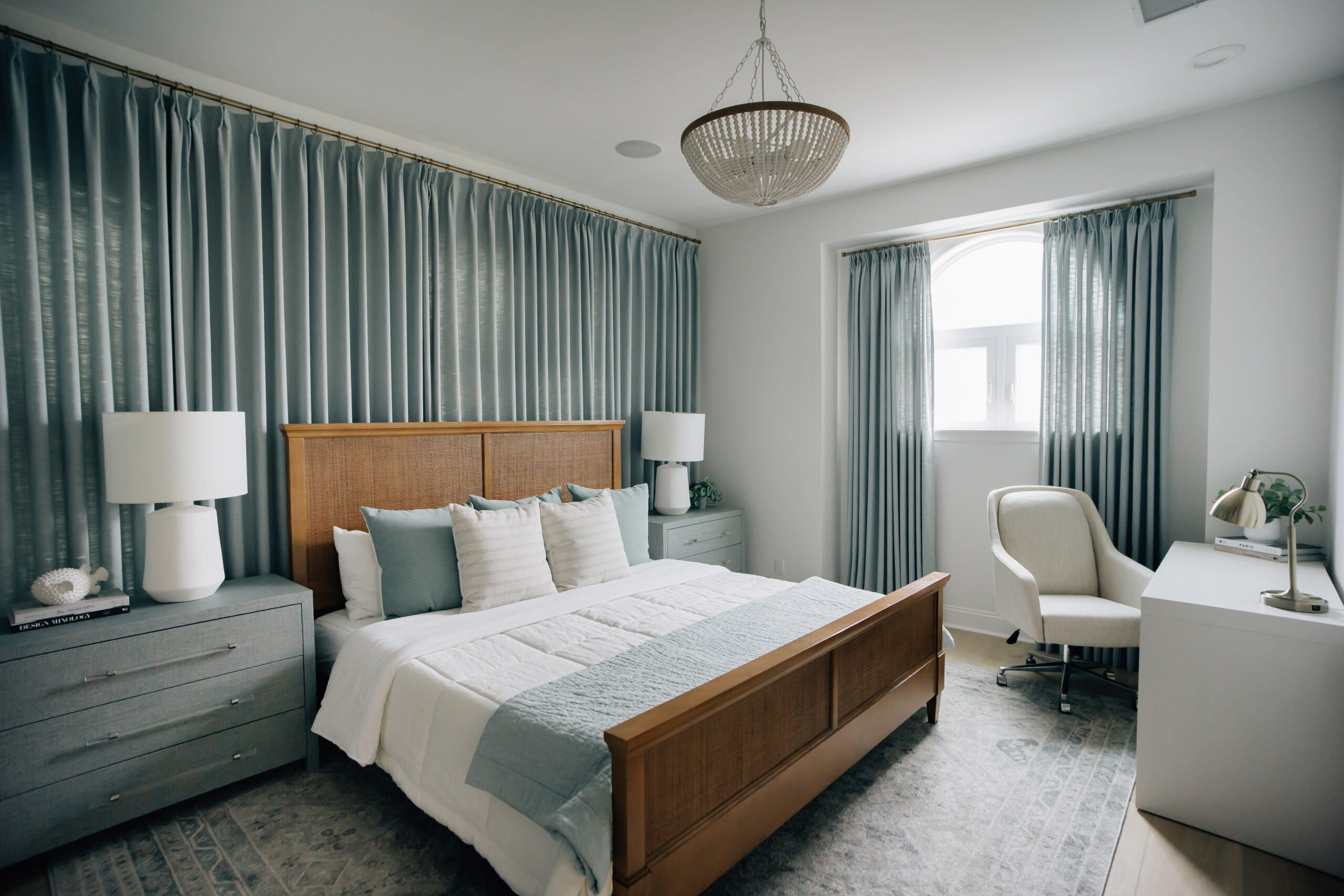 Cozy bedroom with a primarily white and blue color palette. 