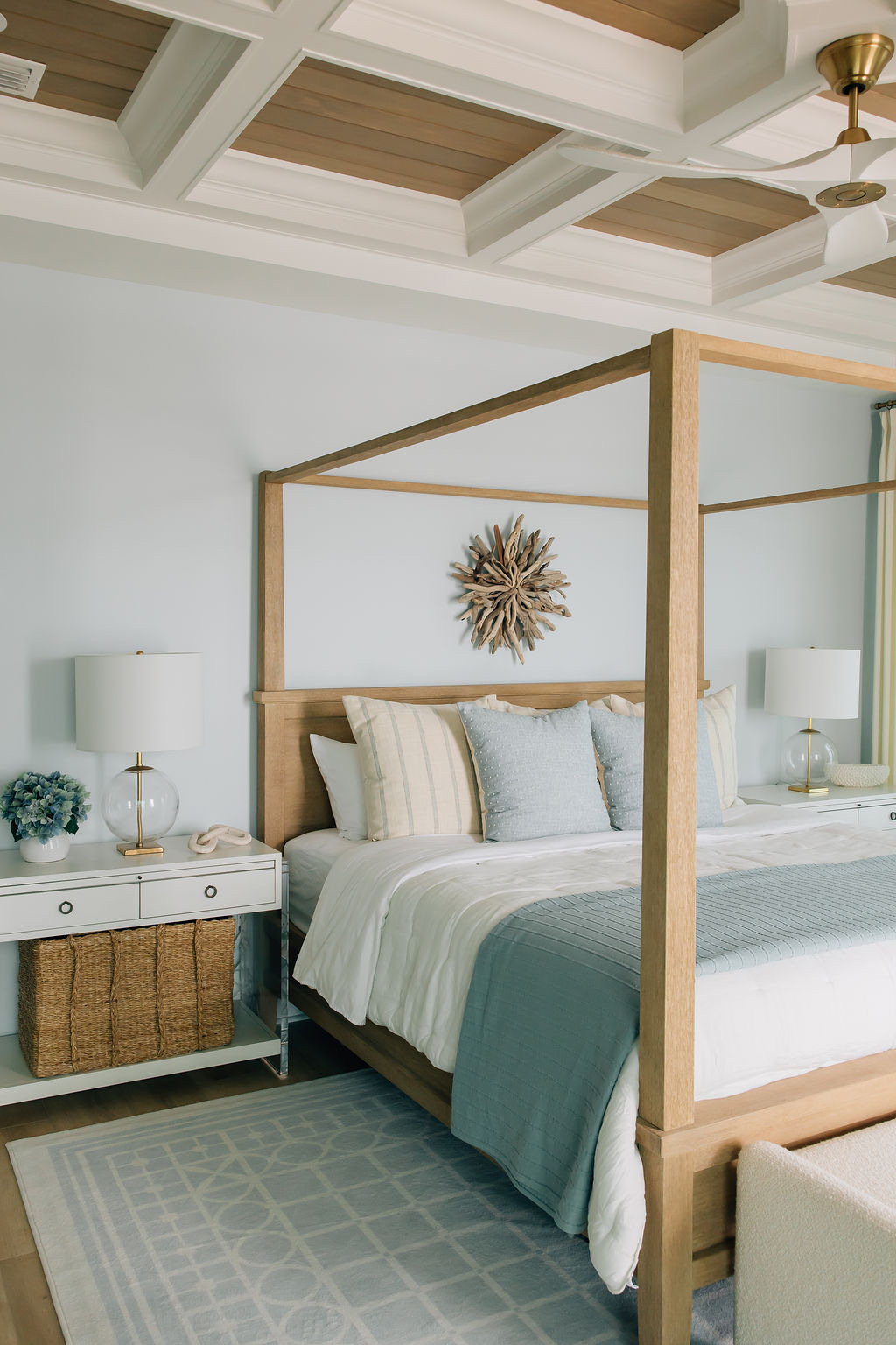 Coastal inspired bedroom with custom tray ceiling, natural wood accents, pops of coastal blue, and beautiful features designed by a Florida interior designer.