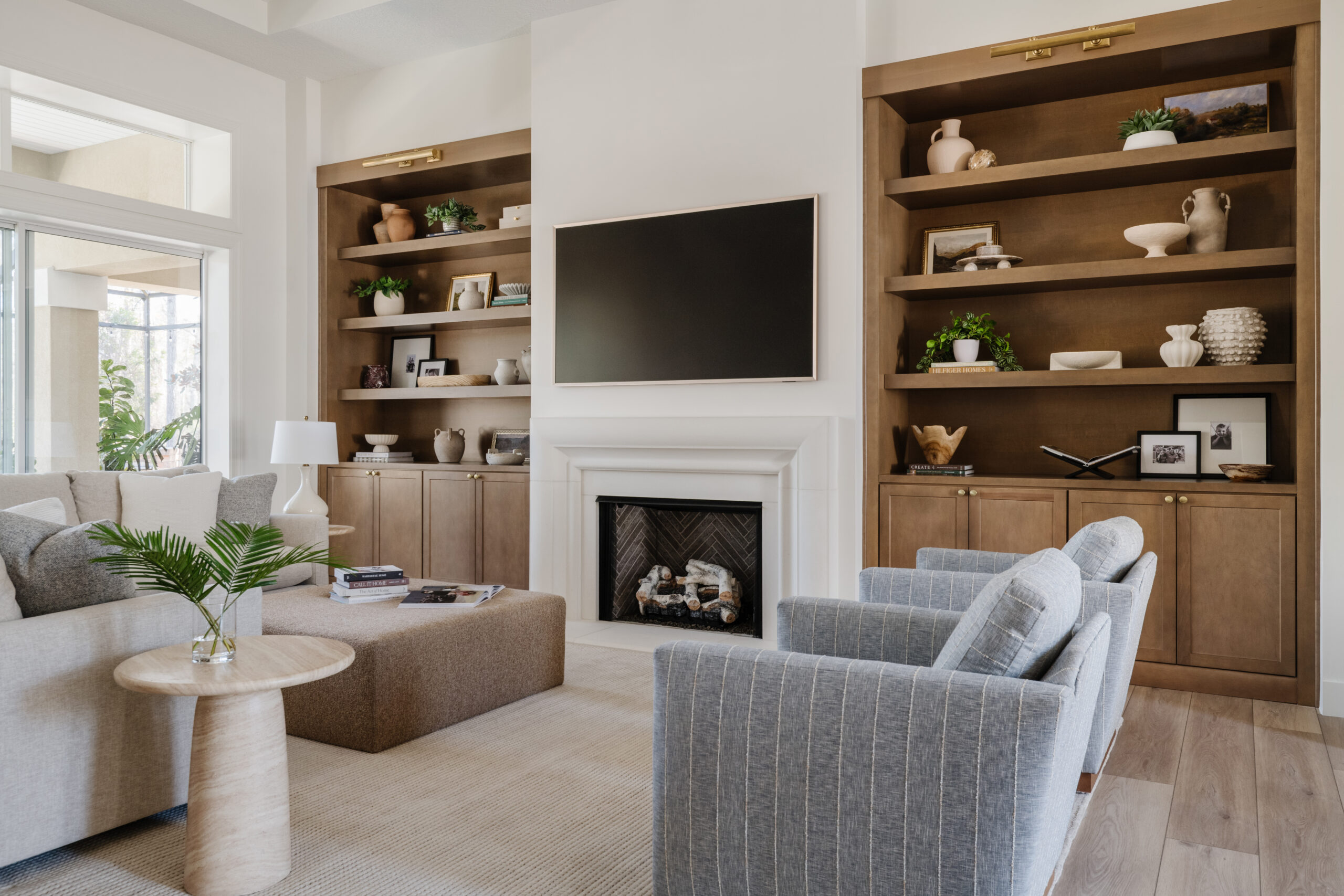 Contemporary living room featuring custom wood built-in shelving, fireplace, wall-mounted television, comfortable seating, and decorative accessories.