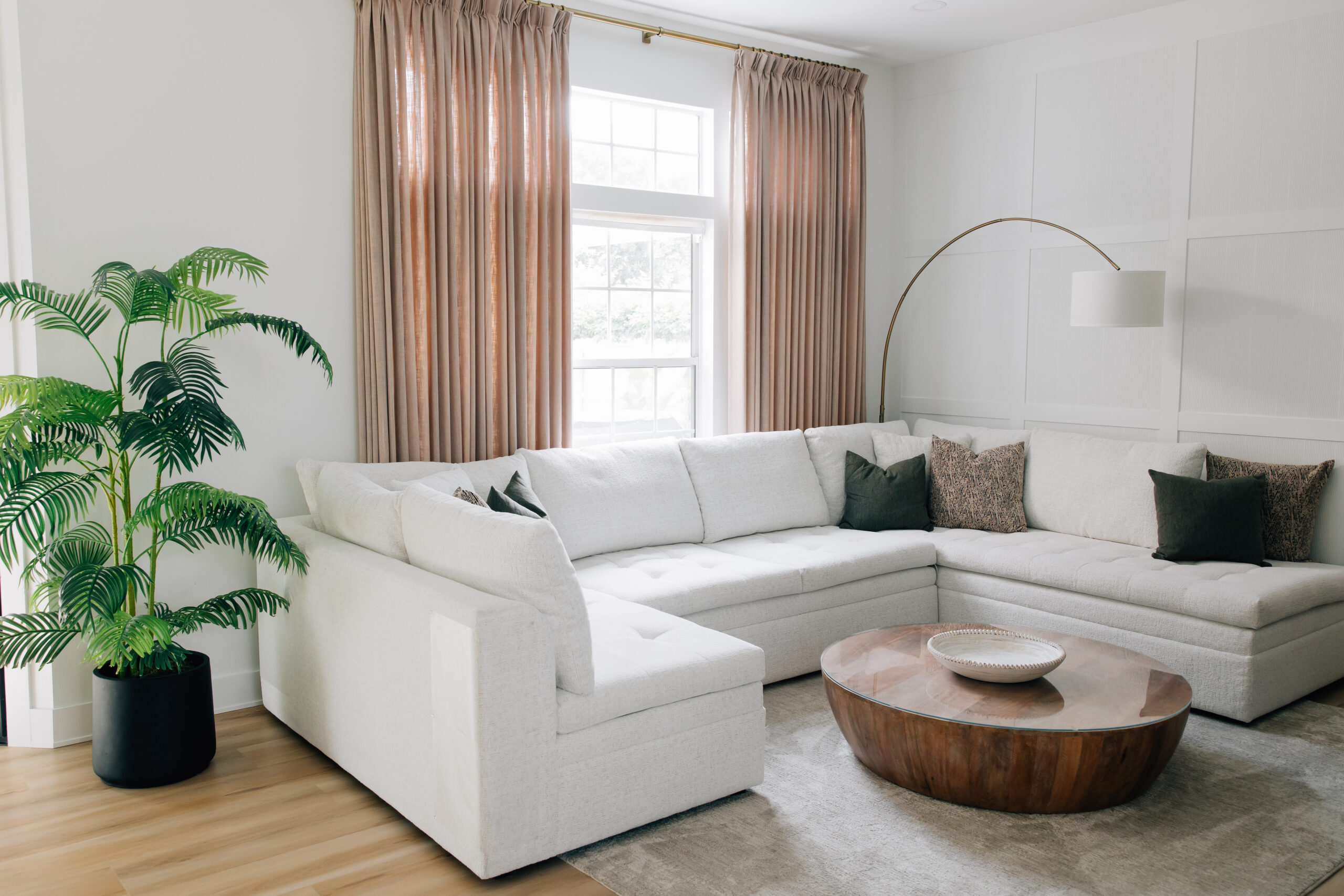 Open-concept living room with a cream sectional and wainscotting accent wall.