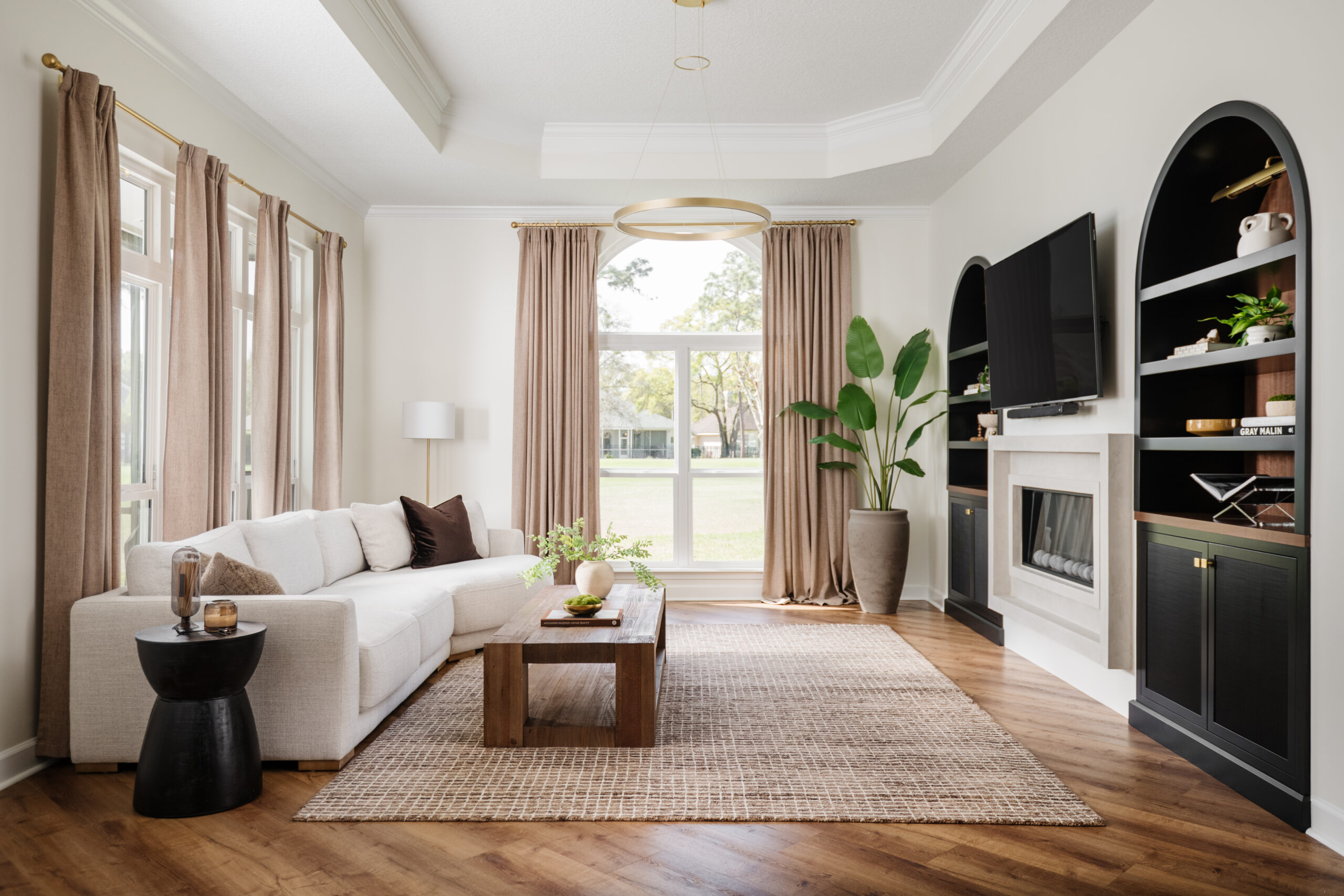 Living room with natural light, neutral sofa, coffee table and built-in shelves.