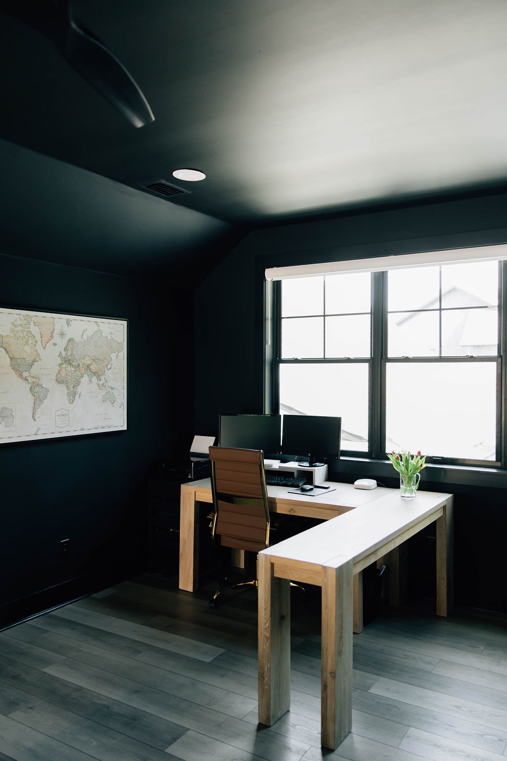 Well-lit office color-drenched in black with minimal decor distractions.